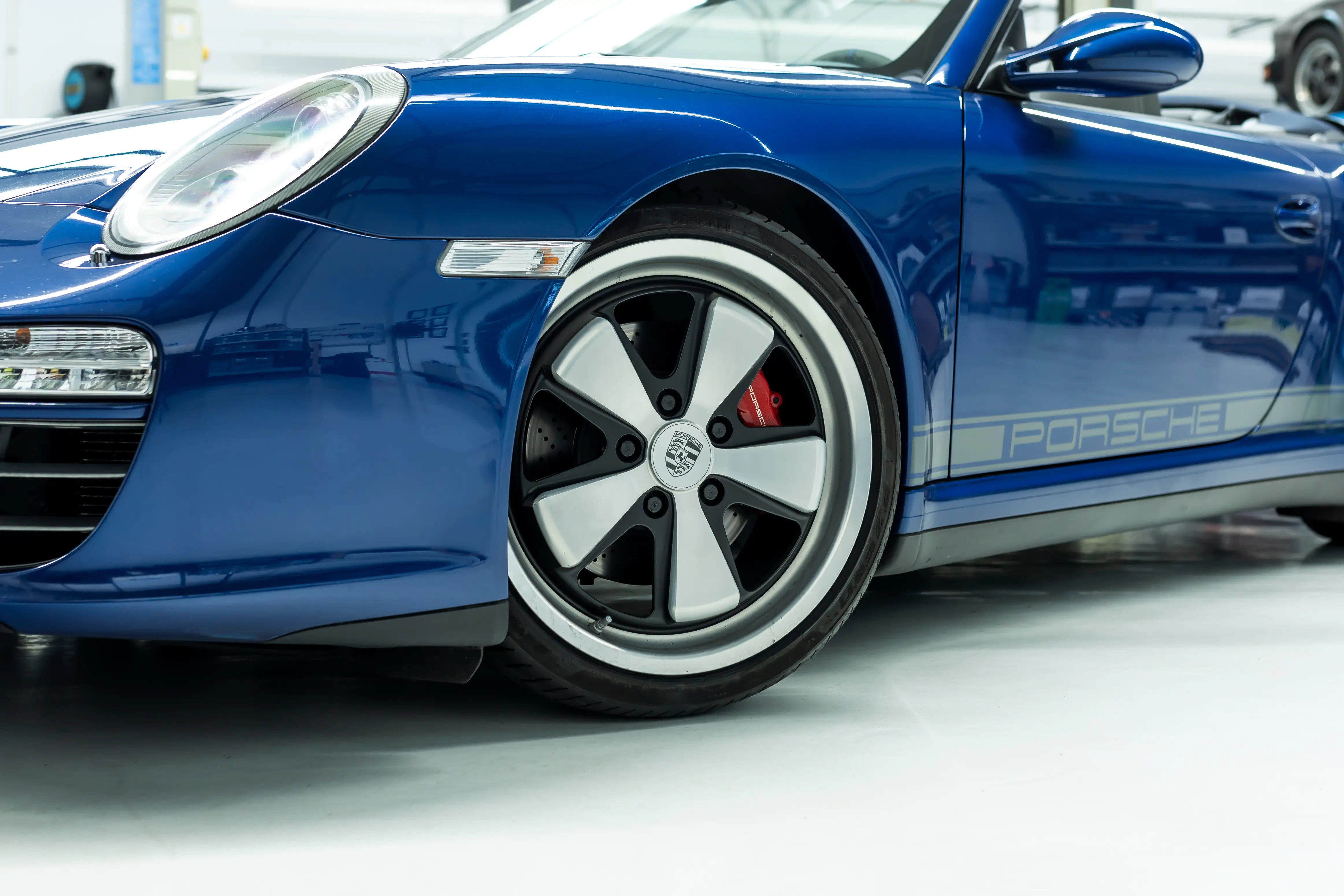 Porsche 997 Aquamarin Fuchs-Felge mit rotem Bremssattel – Radkasten Nahaufnahme
