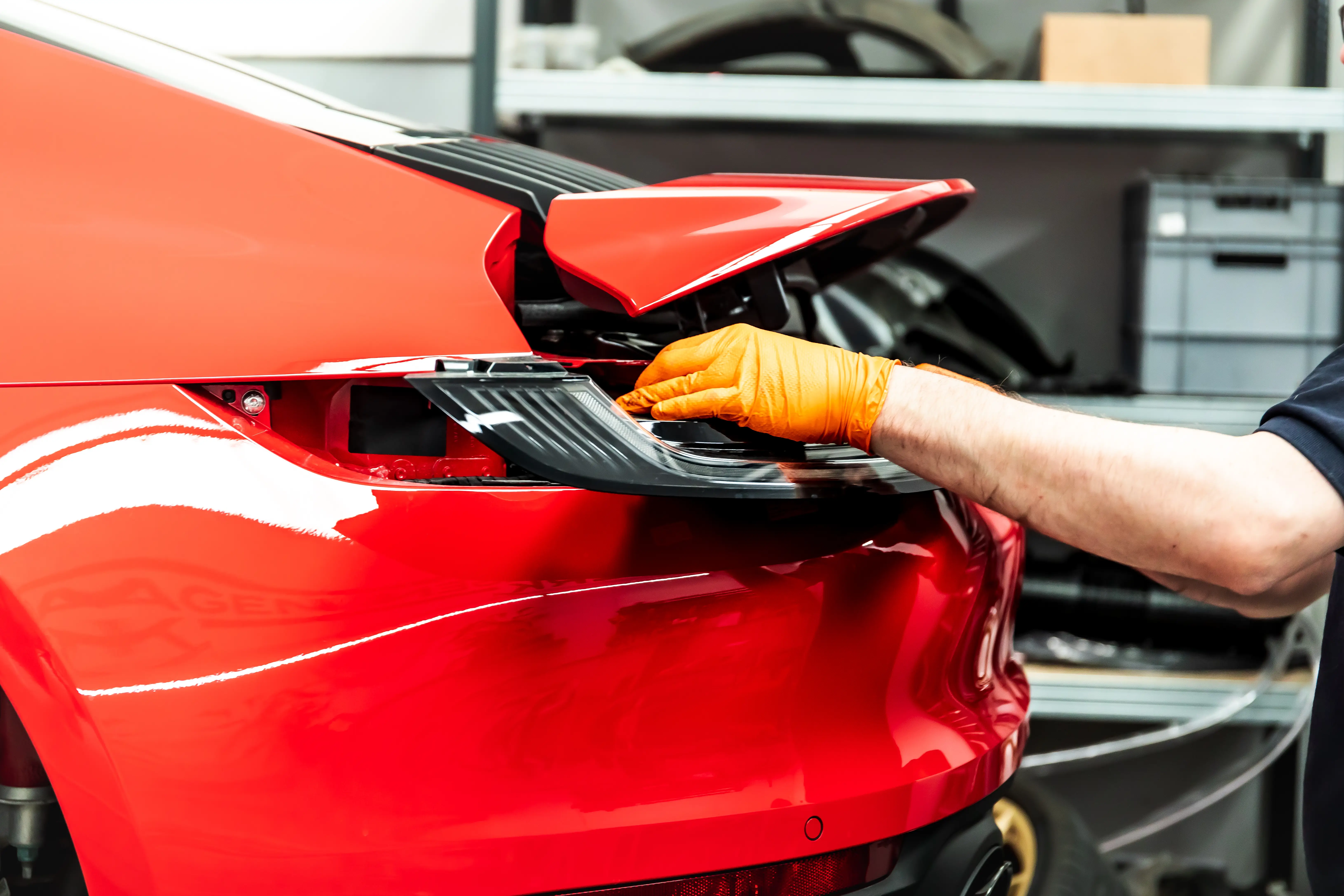 Techniker montiert Rückleuchte am roten Porsche 992 Rubin